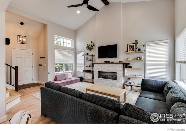 5609 Mount Sanitas Ave, Longmont, CO 80503 - living room with high vaulted ceiling, stairway, a ceiling fan, wood finished floors, and a stone fireplace