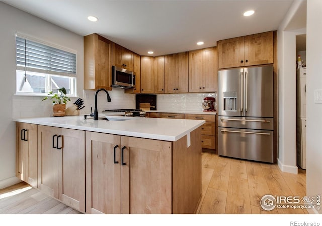 5609 Mount Sanitas Ave, Longmont, CO 80503 - kitchen featuring appliances with stainless steel finishes, a peninsula, light wood finished floors, a sink, and backsplash