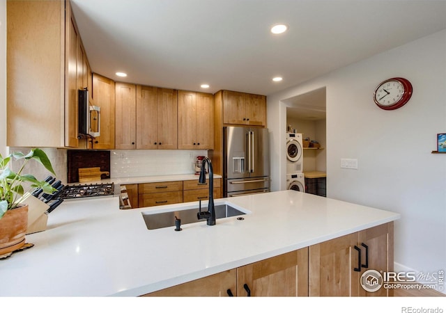 5609 Mount Sanitas Ave, Longmont, CO 80503 - kitchen with stainless steel appliances, a sink, stacked washer and clothes dryer, backsplash, and recessed lighting