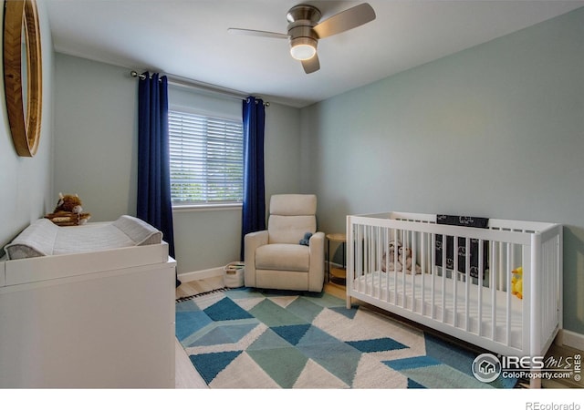 5609 Mount Sanitas Ave, Longmont, CO 80503 - bedroom with baseboards, ceiling fan, a nursery area, and wood finished floors