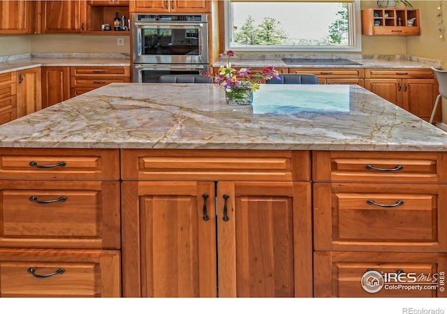 1960 Colard Ln, Lyons, CO 80540 - kitchen with stainless steel double oven, black electric stovetop, brown cabinetry, light stone countertops, and open shelves