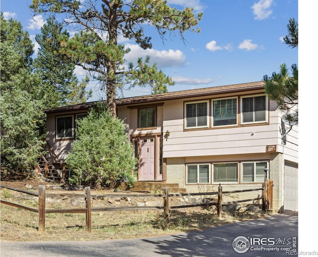 621 Landers St, Estes Park, CO 80517 - split foyer home with a fenced front yard, brick siding, a garage, and asphalt driveway