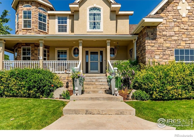1451 Red Fox Cir, Severance, CO 80550 - view of front of home featuring stucco siding, stone siding, a porch, and a front yard