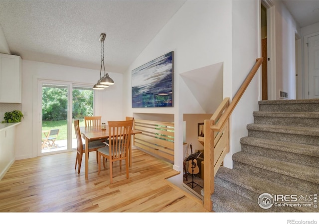 137 S Polk Ave, Louisville, CO 80027 - dining room with light wood-type flooring, vaulted ceiling, stairway, and a textured ceiling