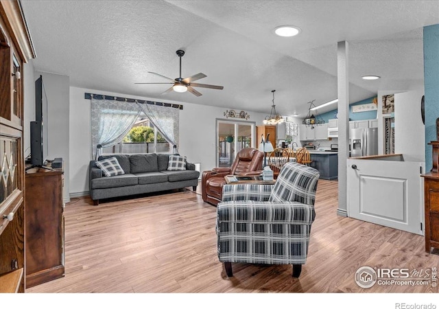 110 50th Ave, Greeley, CO 80634 - living room with vaulted ceiling, a textured ceiling, ceiling fan, light wood finished floors, and a chandelier