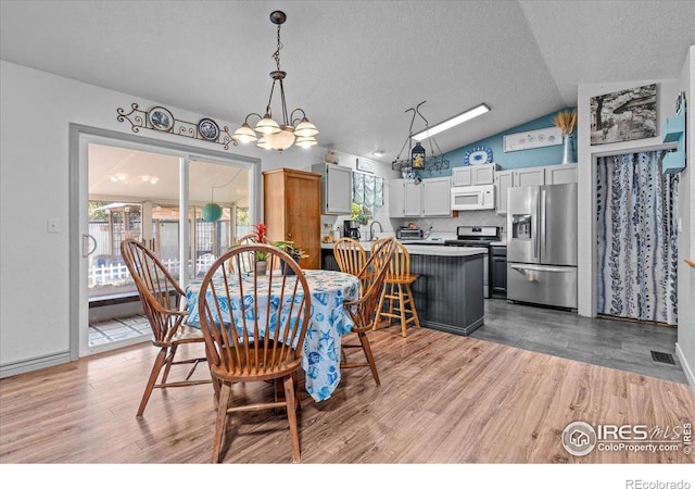 110 50th Ave, Greeley, CO 80634 - dining room featuring vaulted ceiling, light wood finished floors, a chandelier, and a textured ceiling