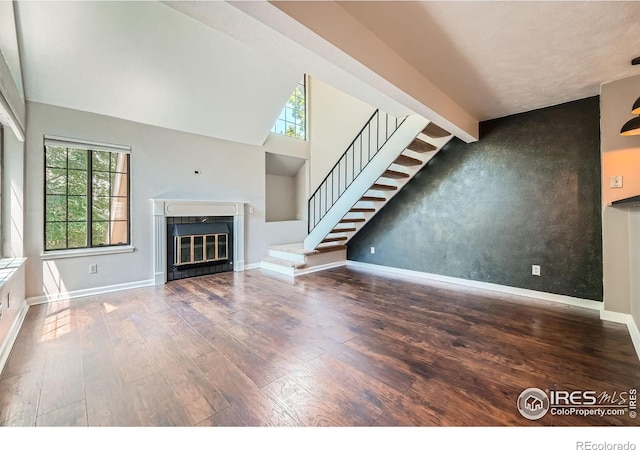 4771 White Rock Cir Unit B, Boulder, CO 80301 - unfurnished living room featuring wood-type flooring, stairway, a glass covered fireplace, and a towering ceiling