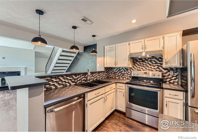 4771 White Rock Cir Unit B, Boulder, CO 80301 - kitchen with stainless steel appliances, dark countertops, a peninsula, under cabinet range hood, and hanging light fixtures
