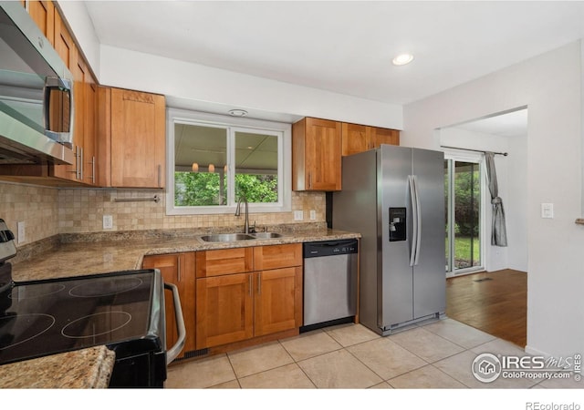 1512 Brentwood Dr, Fort Collins, CO 80521 - kitchen featuring appliances with stainless steel finishes, brown cabinetry, decorative backsplash, light tile patterned floors, and plenty of natural light