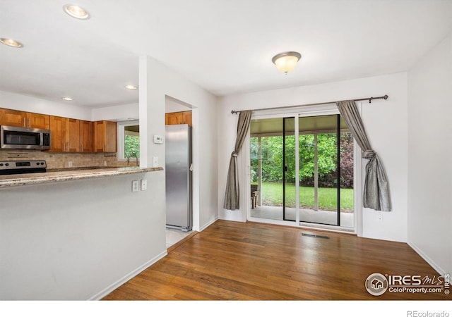 1512 Brentwood Dr, Fort Collins, CO 80521 - kitchen featuring appliances with stainless steel finishes, brown cabinetry, plenty of natural light, wood finished floors, and recessed lighting