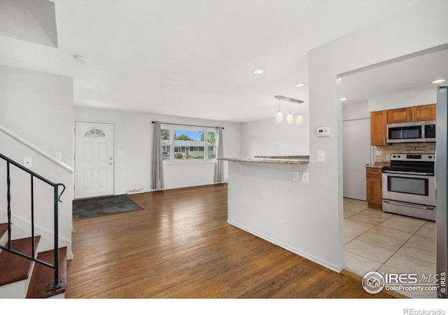 1512 Brentwood Dr, Fort Collins, CO 80521 - kitchen featuring appliances with stainless steel finishes, brown cabinets, light wood-style flooring, decorative backsplash, and open floor plan