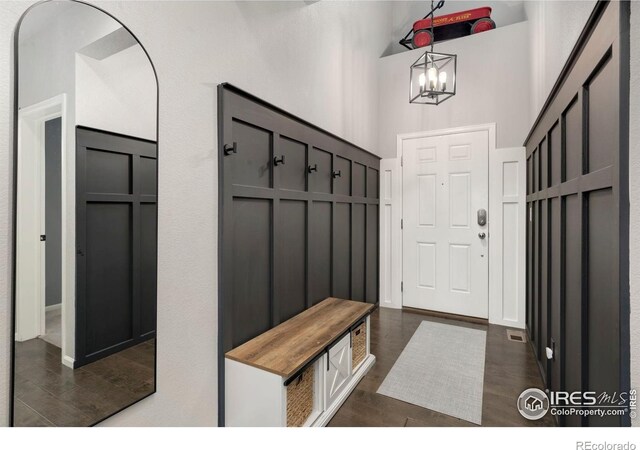 6420 Tuxedo Park Rd, Timnath, CO 80547 - mudroom featuring a chandelier, a towering ceiling, and dark wood-style flooring