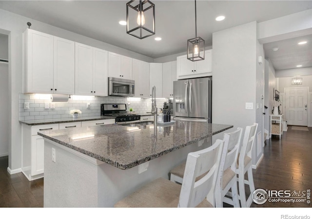 6420 Tuxedo Park Rd, Timnath, CO 80547 - kitchen with stainless steel appliances, dark wood-style flooring, dark stone counters, tasteful backsplash, and recessed lighting