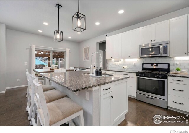 6420 Tuxedo Park Rd, Timnath, CO 80547 - kitchen featuring stainless steel appliances, dark wood-type flooring, decorative backsplash, recessed lighting, and light stone counters