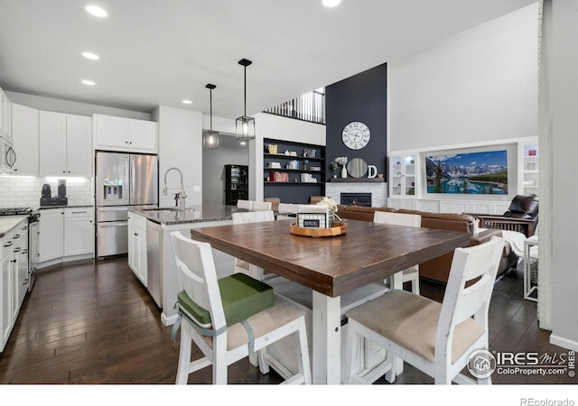 6420 Tuxedo Park Rd, Timnath, CO 80547 - dining room featuring dark wood-style floors, a lit fireplace, and recessed lighting