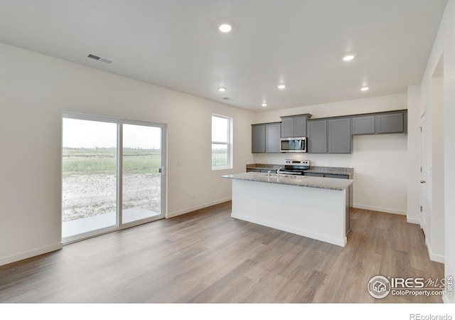 1639 Pinnacle Ave, Lochbuie, CO 80603 - kitchen with appliances with stainless steel finishes, gray cabinetry, light wood-style floors, a kitchen island with sink, and recessed lighting
