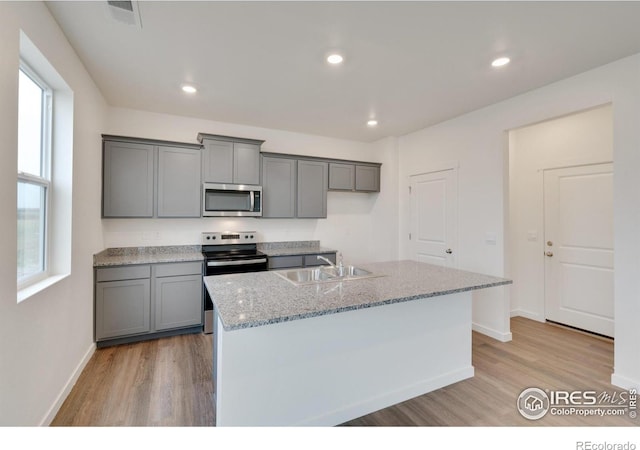 1639 Pinnacle Ave, Lochbuie, CO 80603 - kitchen with appliances with stainless steel finishes, light wood finished floors, gray cabinetry, light stone counters, and recessed lighting