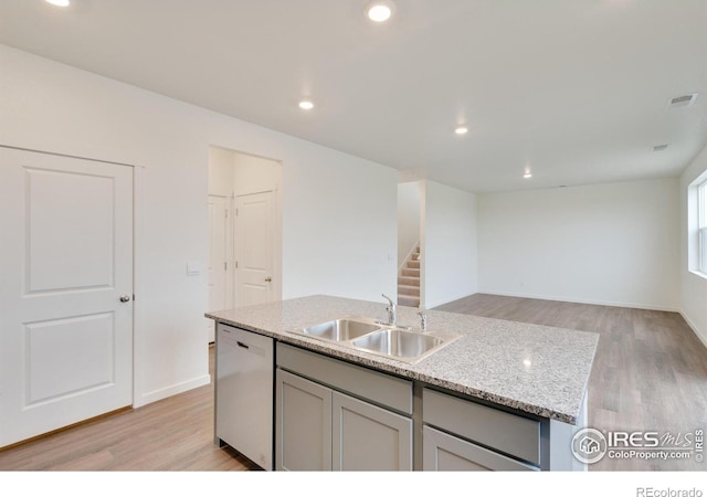 1639 Pinnacle Ave, Lochbuie, CO 80603 - kitchen with dishwasher, light wood-style flooring, an island with sink, light stone counters, and recessed lighting