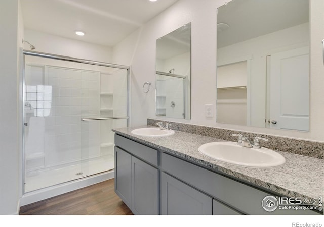 1639 Pinnacle Ave, Lochbuie, CO 80603 - full bathroom with a stall shower, wood finished floors, double vanity, and a spacious closet