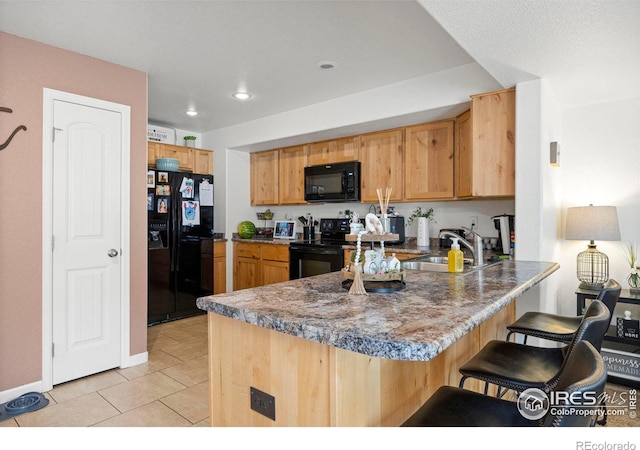 3145 Alybar Dr # 16B, Wellington, CO 80549 - kitchen featuring black appliances, a peninsula, a kitchen bar, light tile patterned floors, and recessed lighting