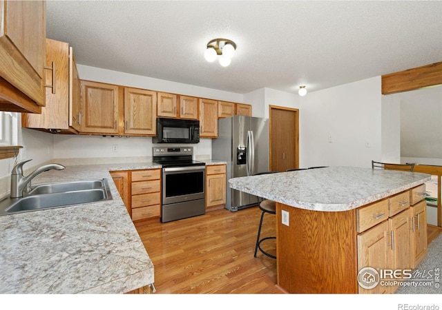 4222 W 22nd Street Rd, Greeley, CO 80634 - kitchen featuring appliances with stainless steel finishes, light countertops, light wood-style floors, a center island, and a kitchen bar