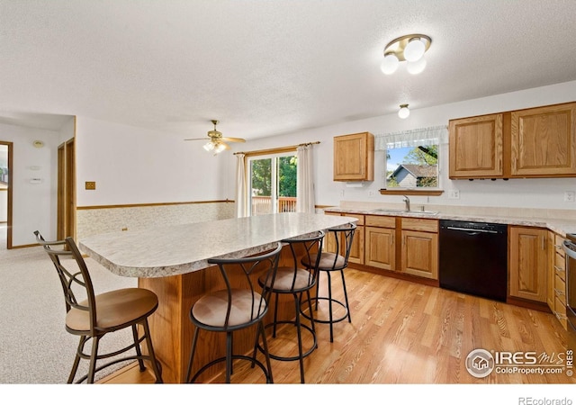 4222 W 22nd Street Rd, Greeley, CO 80634 - kitchen with black dishwasher, a textured ceiling, a kitchen bar, and light countertops
