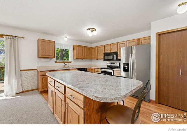 4222 W 22nd Street Rd, Greeley, CO 80634 - kitchen with black appliances, light countertops, a kitchen island, a textured ceiling, and a breakfast bar