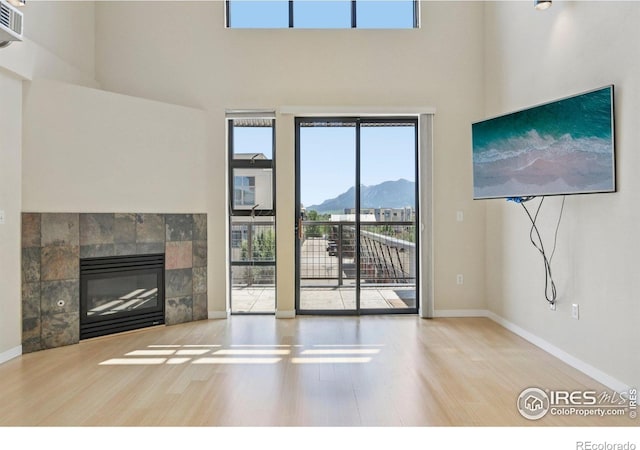 1200 Yarmouth Ave Unit 237, Boulder, CO 80304 - unfurnished living room with wood finished floors, a high ceiling, and a tiled fireplace