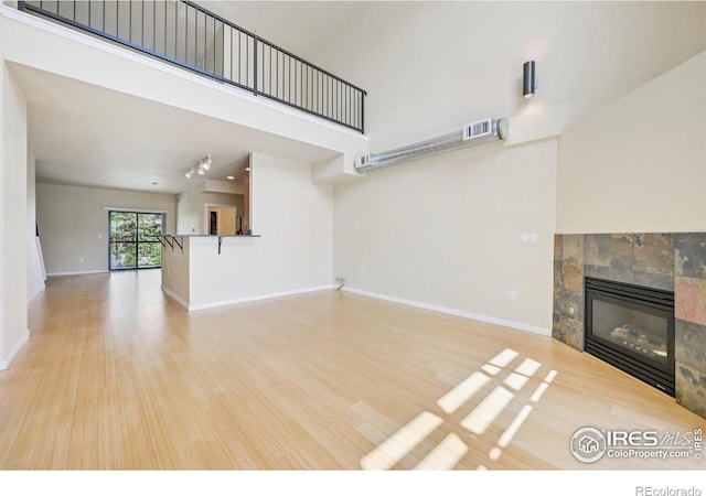 1200 Yarmouth Ave Unit 237, Boulder, CO 80304 - unfurnished living room featuring wood finished floors, a tiled fireplace, and a towering ceiling