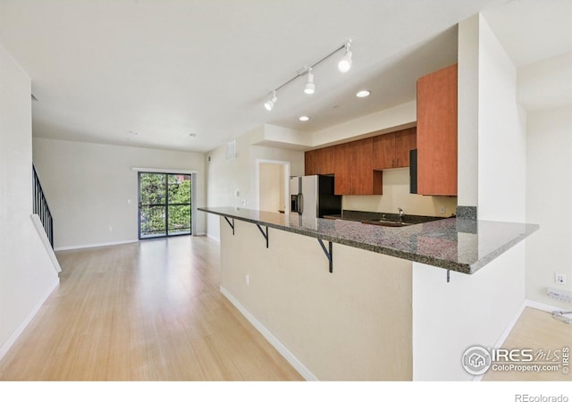 1200 Yarmouth Ave Unit 237, Boulder, CO 80304 - kitchen featuring refrigerator with ice dispenser, brown cabinetry, a breakfast bar area, and light wood-style flooring