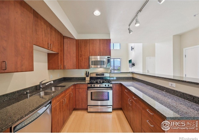 1200 Yarmouth Ave Unit 237, Boulder, CO 80304 - kitchen with appliances with stainless steel finishes, brown cabinetry, dark stone counters, and rail lighting