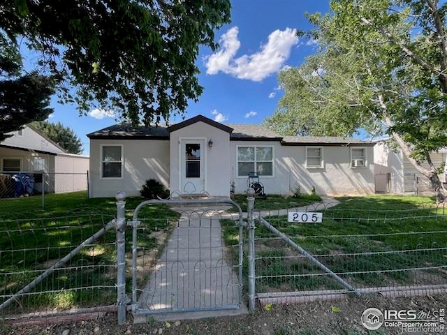 205-207 W 3rd Ave, Wiggins, CO 80654 - ranch-style house with stucco siding and a gate