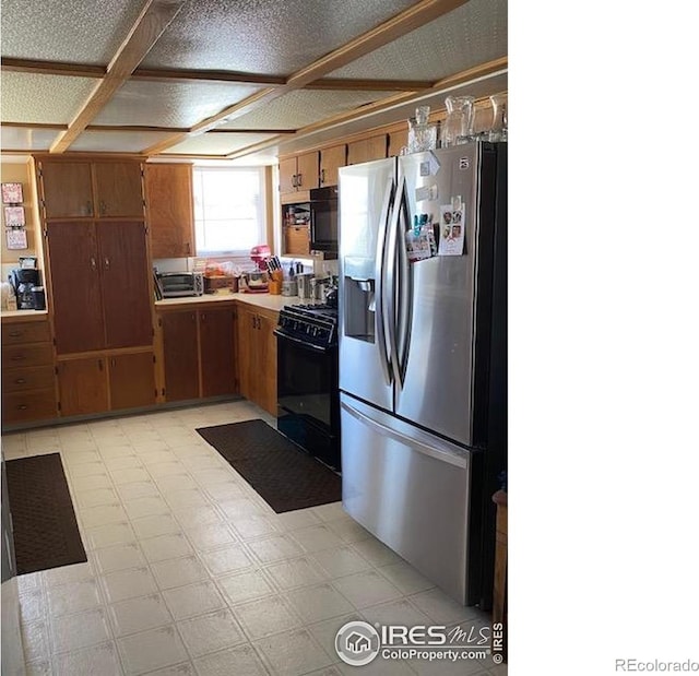 205-207 W 3rd Ave, Wiggins, CO 80654 - kitchen with stainless steel fridge, gas stove, light flooring, brown cabinetry, and light countertops