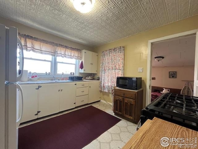 205-207 W 3rd Ave, Wiggins, CO 80654 - kitchen featuring black appliances, light countertops, white cabinets, and an ornate ceiling