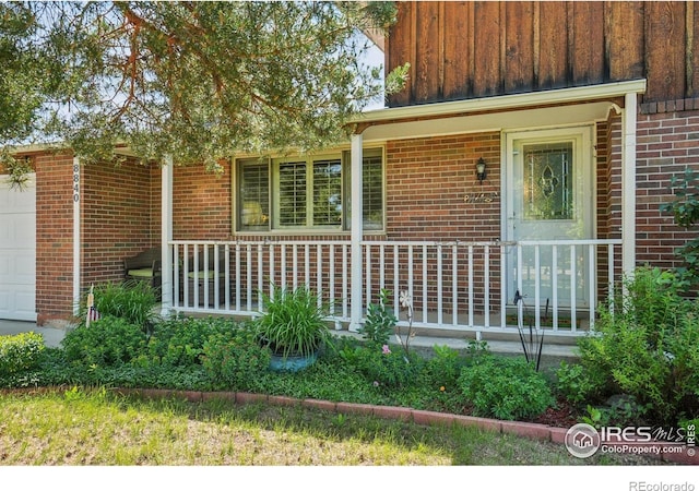 8840 Niwot Rd, Niwot, CO 80503 - view of exterior entry with a garage, a porch, brick siding, and board and batten siding