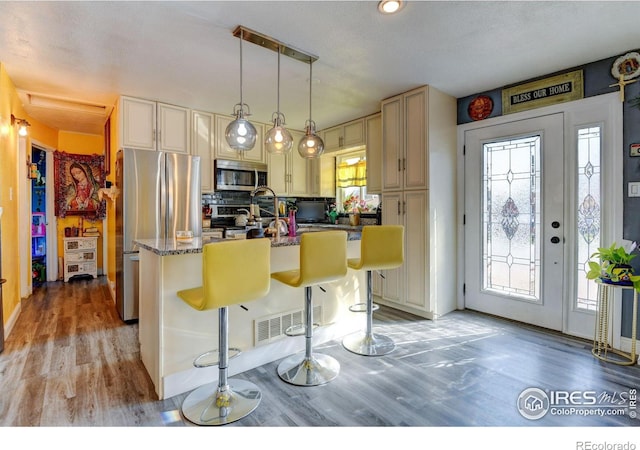 7970 Wolff Ct, Westminster, CO 80030 - kitchen with appliances with stainless steel finishes, cream cabinets, light wood-type flooring, and an island with sink