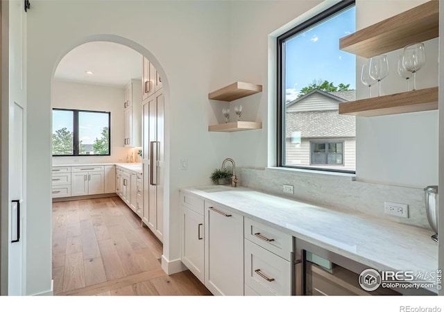 1126 W Enclave Cir, Louisville, CO 80027 - kitchen featuring open shelves, arched walkways, white cabinetry, and light wood-style floors