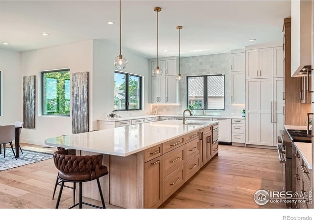1126 W Enclave Cir, Louisville, CO 80027 - kitchen with high end range, light countertops, light wood-type flooring, a kitchen breakfast bar, and recessed lighting