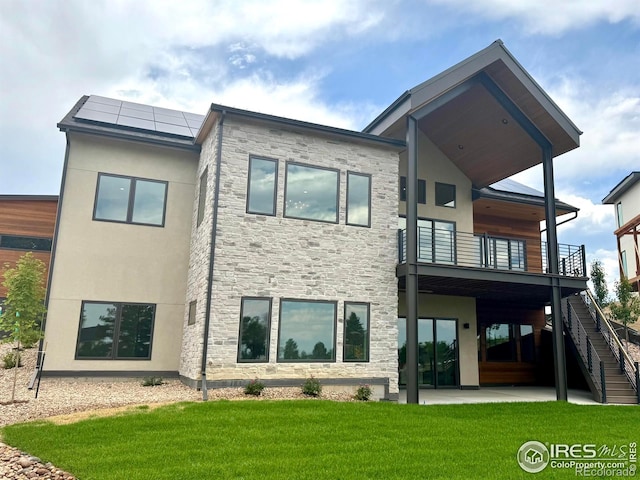 1126 W Enclave Cir, Louisville, CO 80027 - rear view of house with a patio, stone siding, solar panels, a lawn, and a balcony