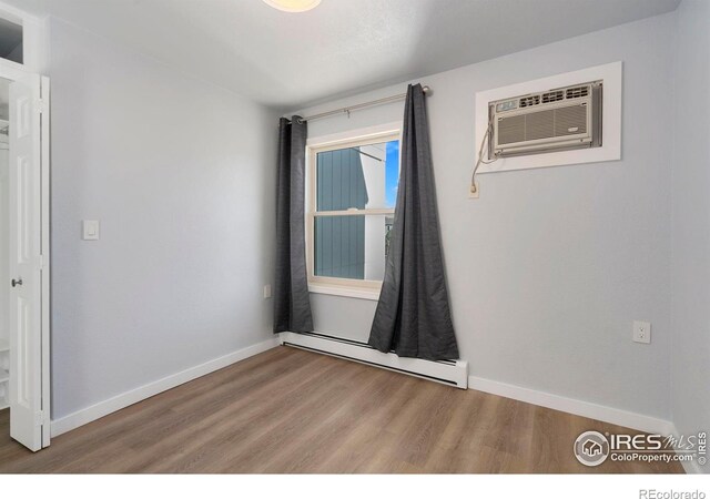 512 E Monroe Dr Unit 329, Fort Collins, CO 80525 - unfurnished room with a baseboard radiator, wood finished floors, and a wall mounted air conditioner