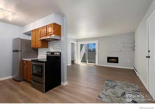 512 E Monroe Dr Unit 329, Fort Collins, CO 80525 - kitchen featuring stainless steel appliances, under cabinet range hood, baseboard heating, light wood-style flooring, and backsplash