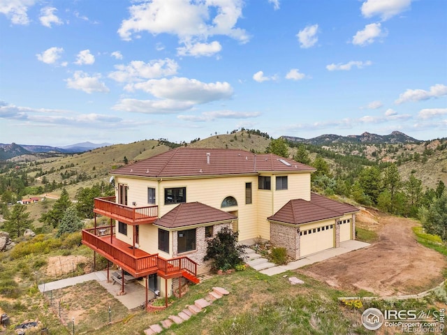 366 N Rim Rd, Livermore, CO 80536 - rear view of house featuring a garage, driveway, a balcony, a deck with mountain view, and a tiled roof