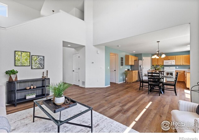 7266 Andover St, Wellington, CO 80549 - living room featuring wood finished floors, a chandelier, a high ceiling, and recessed lighting
