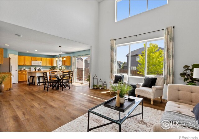7266 Andover St, Wellington, CO 80549 - living room with a chandelier, wood finished floors, a high ceiling, and recessed lighting