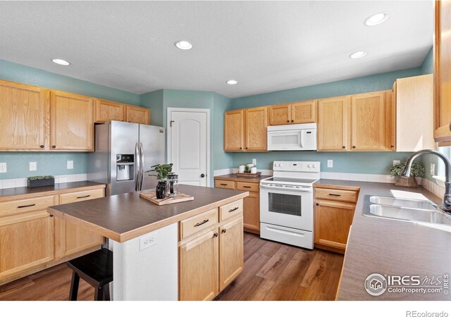 7266 Andover St, Wellington, CO 80549 - kitchen featuring white appliances, light brown cabinets, recessed lighting, a center island, and wood finished floors