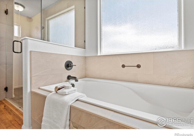 7266 Andover St, Wellington, CO 80549 - bathroom with a stall shower, a bath, and wood finished floors