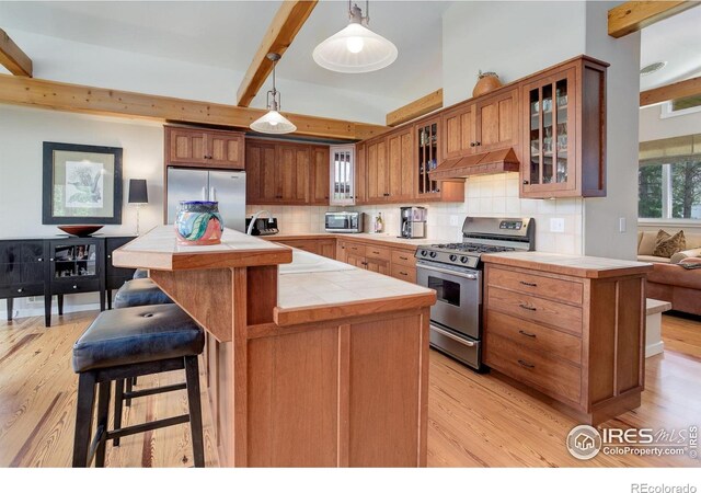 9445 Lykins Pl, Boulder, CO 80301 - kitchen with stainless steel appliances, tile counters, custom range hood, beam ceiling, and light wood finished floors