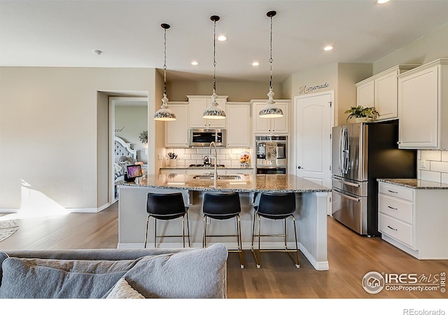 2050 Vineyard Dr, Windsor, CO 80550 - kitchen featuring stainless steel appliances, dark wood-style floors, decorative backsplash, a breakfast bar, and recessed lighting