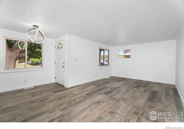 1111 Wabash St, Denver, CO 80220 - unfurnished living room featuring healthy amount of natural light, wood finished floors, a textured ceiling, and a chandelier
