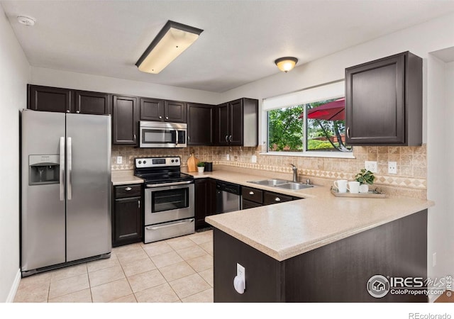 1667 Reliance Cir, Superior, CO 80027 - kitchen featuring appliances with stainless steel finishes, light countertops, backsplash, a peninsula, and light tile patterned floors